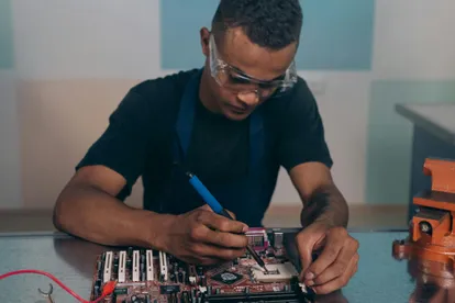 A worker soldering a motherboard